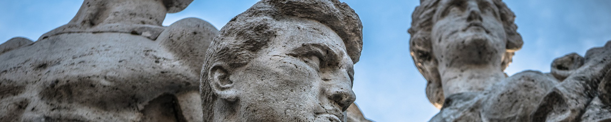 Stone statue in Italy featuring two men and a woman