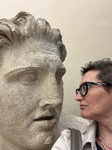 a woman in side profile looks at statue